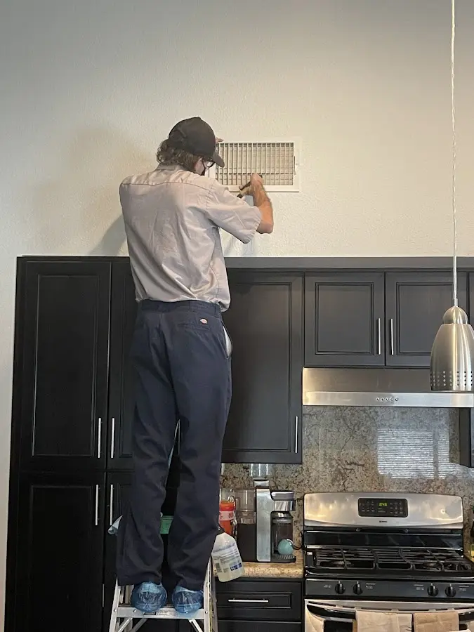 Technician inspecting an air vent during HVAC service in Swainsboro